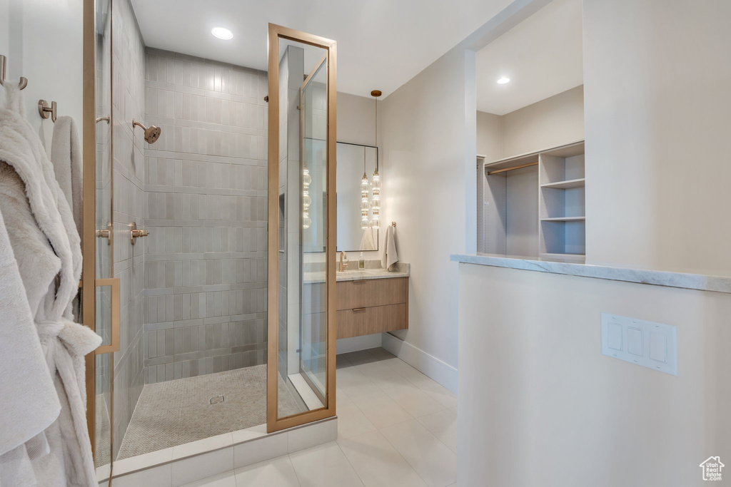 Bathroom with a tile shower, vanity, tile patterned flooring, baseboards, and recessed lighting