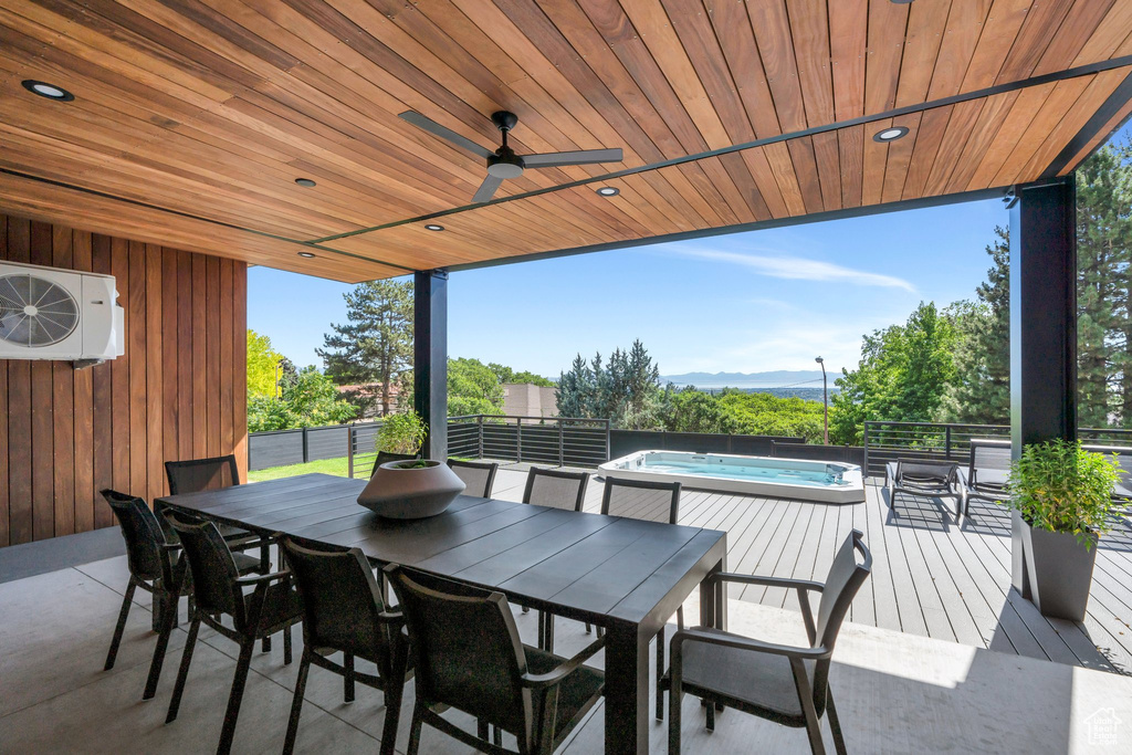 View of patio / terrace with an outdoor hot tub, outdoor dining space, ac unit, a ceiling fan, and a deck with mountain view