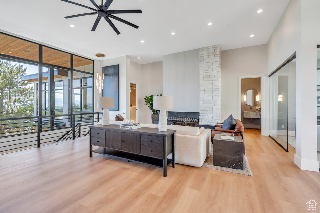 Living area with ceiling fan, light wood-type flooring, expansive windows, recessed lighting, and a fireplace