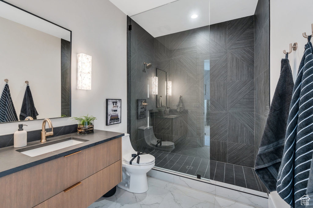 Full bathroom with vanity, toilet, marble look tile flooring, a walk in shower, and recessed lighting