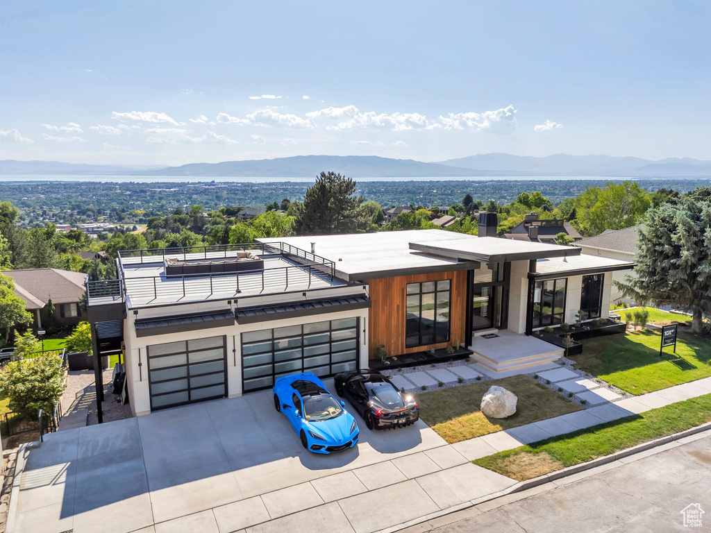 Contemporary home featuring a mountain view, a balcony, concrete driveway, and an attached garage
