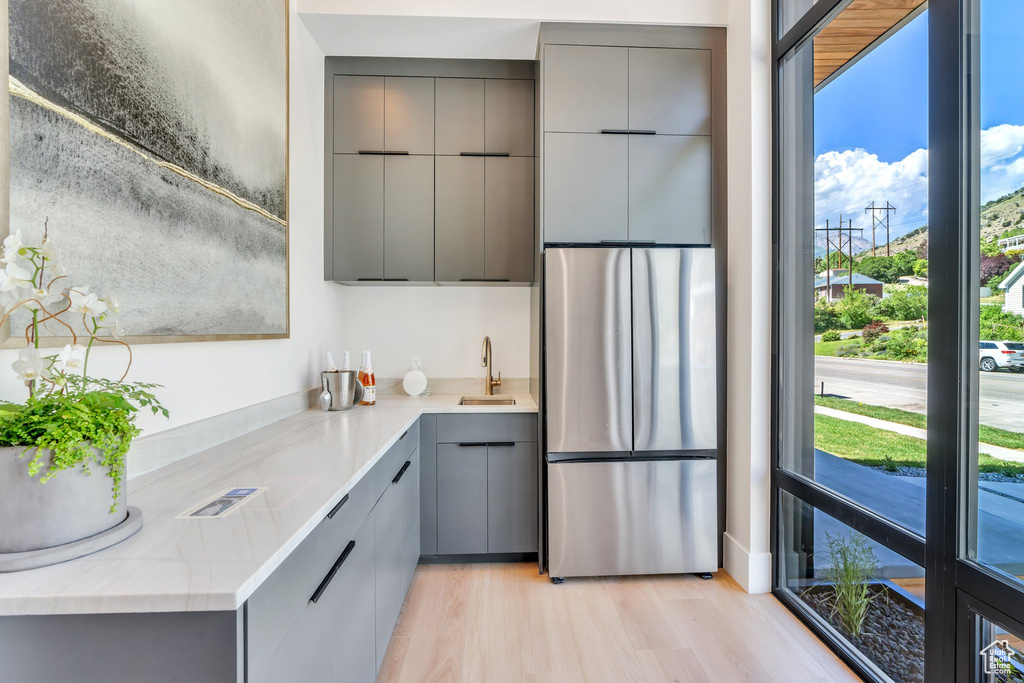 Kitchen with gray cabinets, freestanding refrigerator, modern cabinets, and a sink