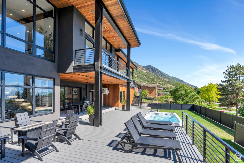 Deck with a fenced backyard, a mountain view, an outdoor hot tub, and outdoor dining space