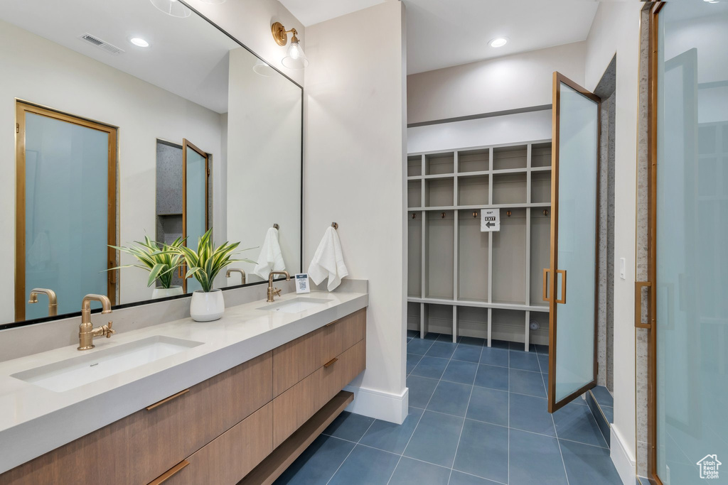 Full bath with double vanity, tile patterned flooring, a spacious closet, and baseboards