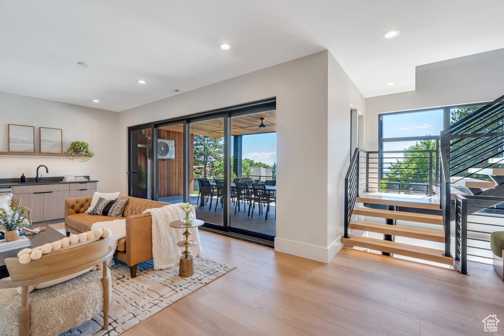 Living area featuring stairway, light wood finished floors, recessed lighting, baseboards, and bar