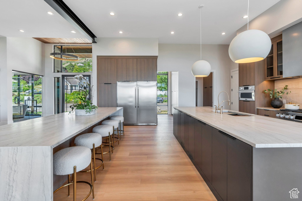 Kitchen featuring appliances with stainless steel finishes, a large island, modern cabinets, a sink, and recessed lighting