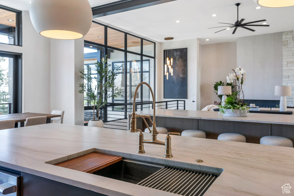 Kitchen with a wall of windows, a sink, recessed lighting, pendant lighting, and ceiling fan