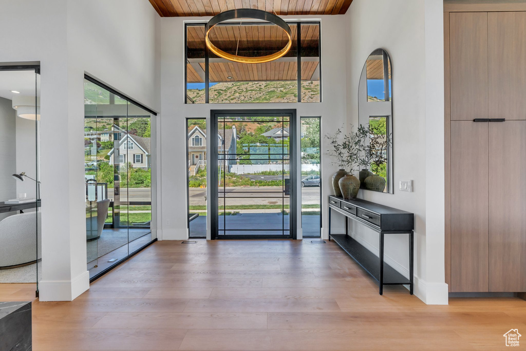 Foyer featuring wood ceiling, a high ceiling, healthy amount of natural light, wood finished floors, and baseboards