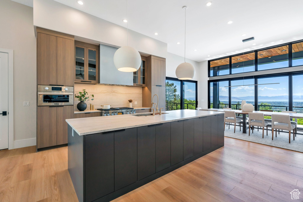 Kitchen featuring a sink, modern cabinets, a large island with sink, backsplash, and recessed lighting