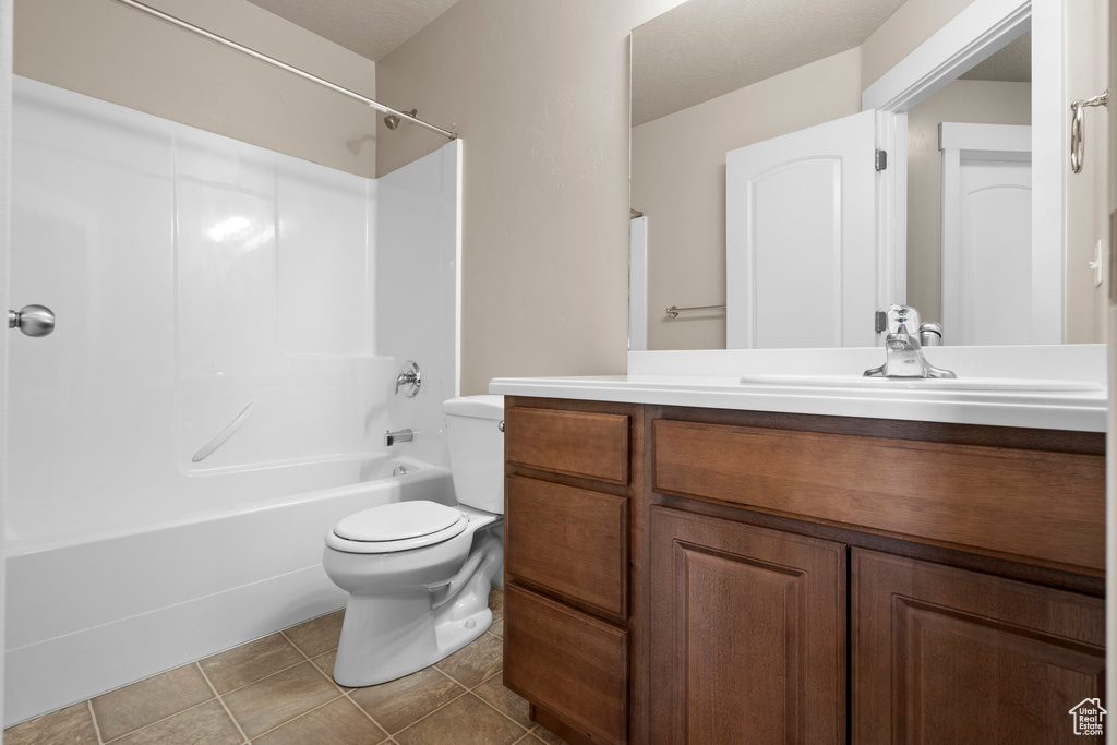 Full bath with bathing tub / shower combination, vanity, toilet, and tile patterned floors