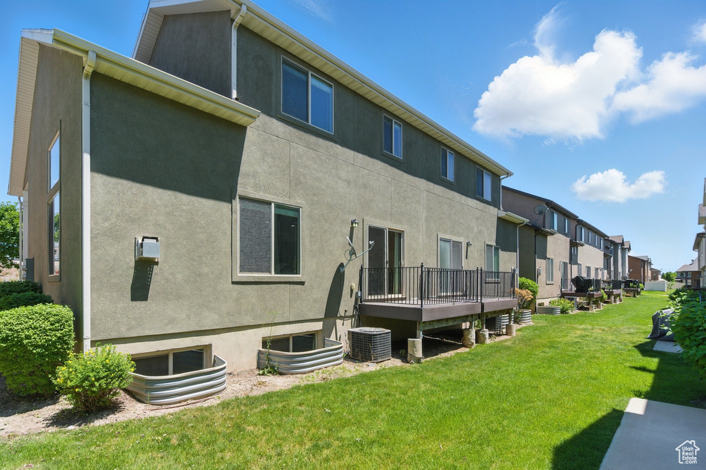 Rear view of property featuring stucco siding, a yard, a residential view, and central air condition unit