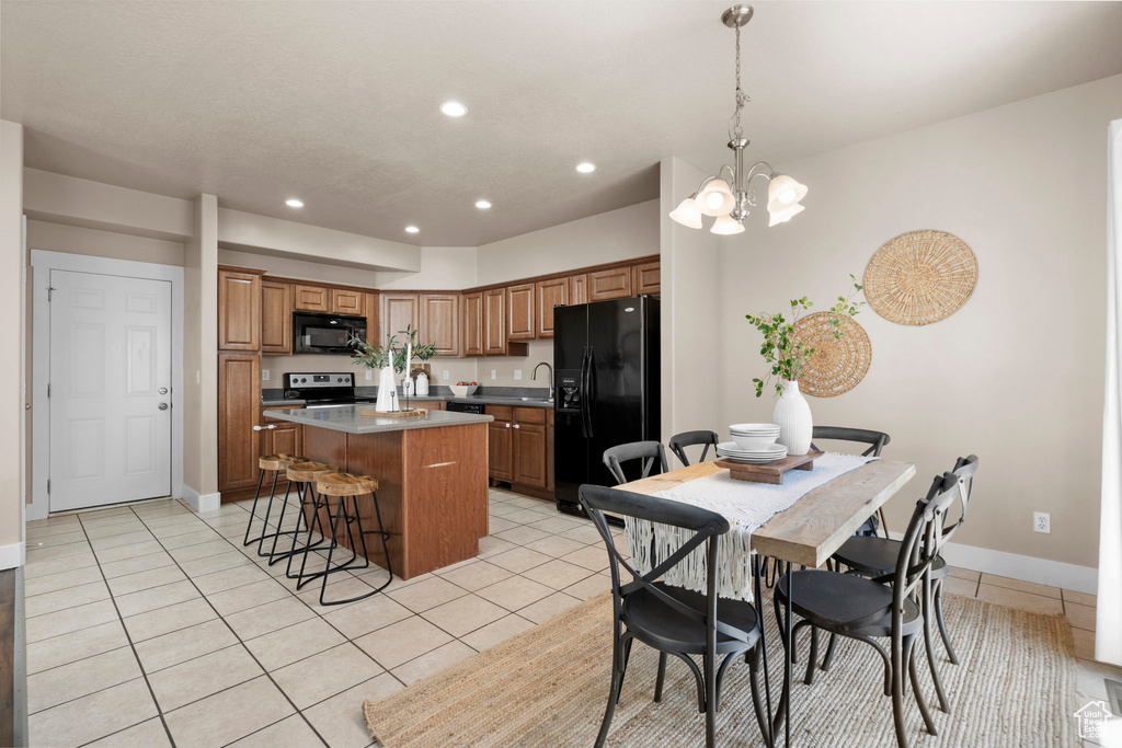 Kitchen featuring black appliances, a center island, light tile patterned flooring, recessed lighting, and brown cabinetry