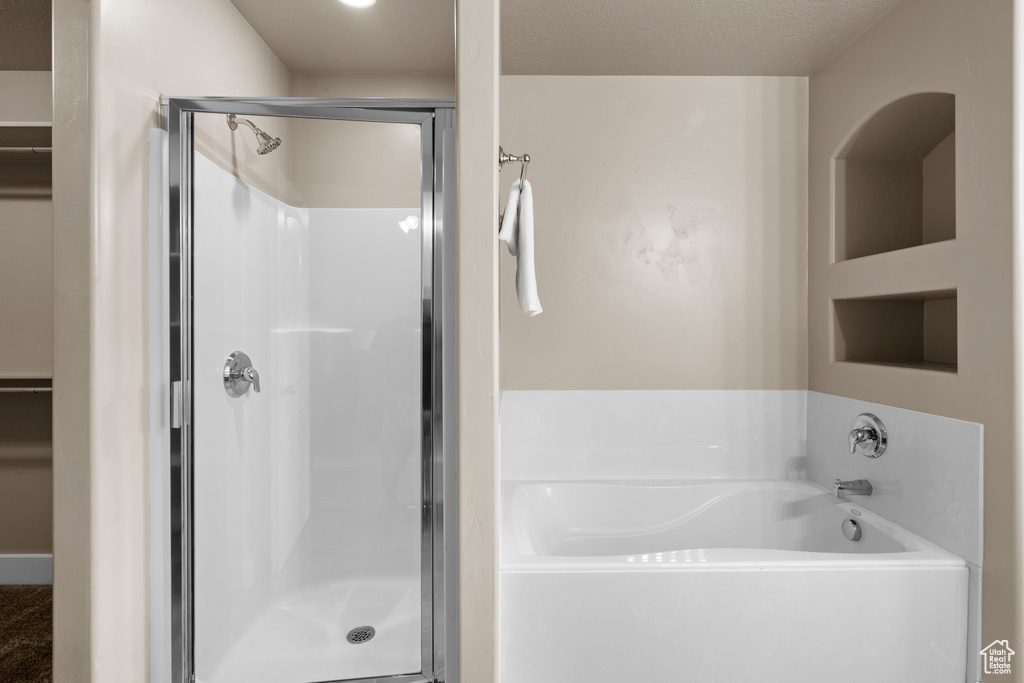 Full bathroom with a shower stall, a bath, and a walk in closet