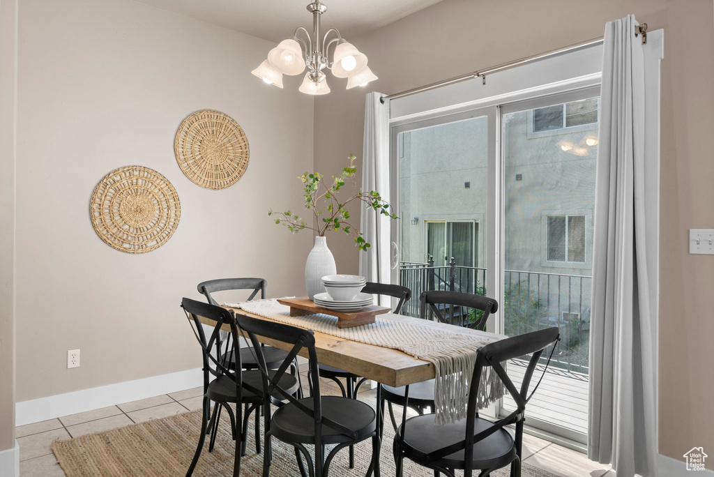 Dining room featuring light tile patterned floors, a chandelier, and baseboards