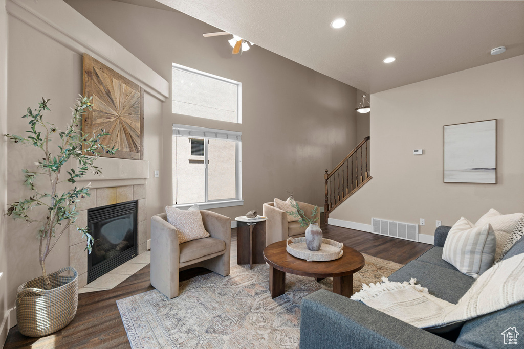 Living room with stairs, a tile fireplace, wood finished floors, a ceiling fan, and recessed lighting