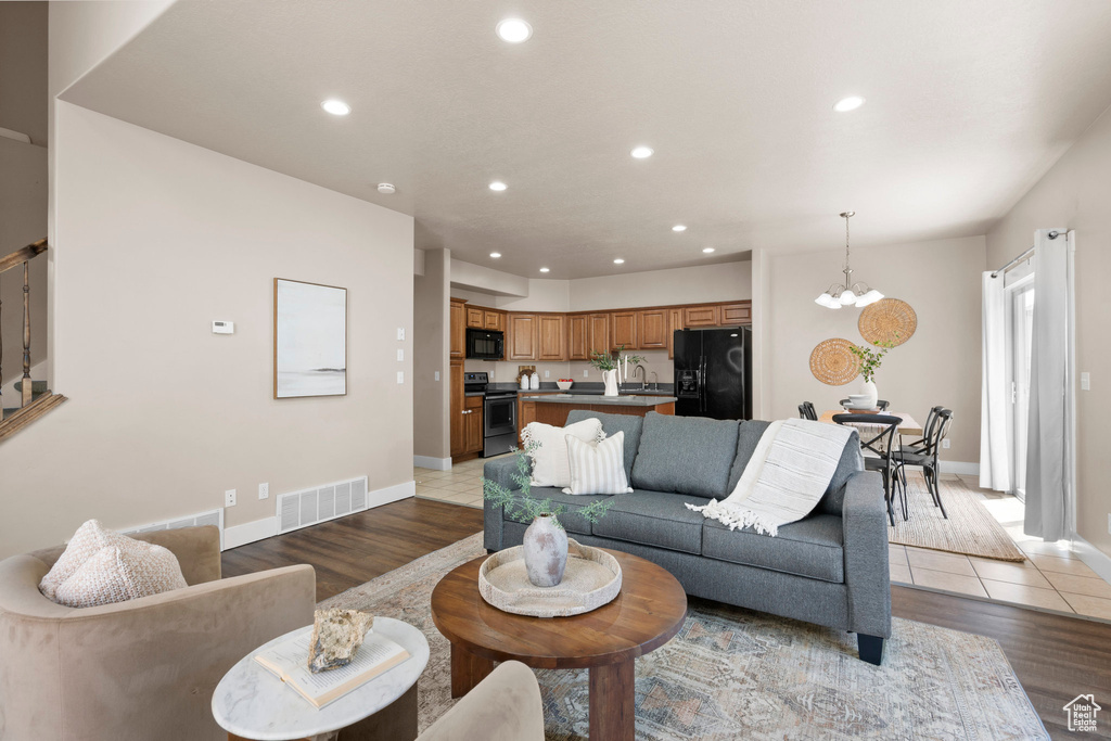 Living room featuring recessed lighting, a chandelier, baseboards, and light wood finished floors