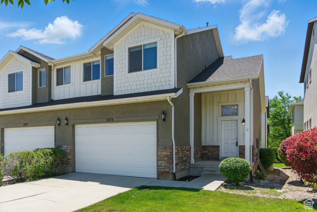 Multi unit property with board and batten siding, stone siding, an attached garage, and concrete driveway