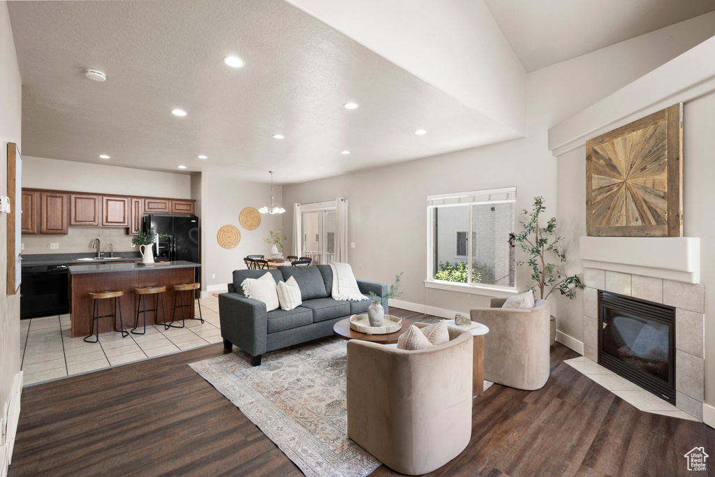 Living area featuring light wood finished floors, recessed lighting, a tile fireplace, baseboards, and a chandelier