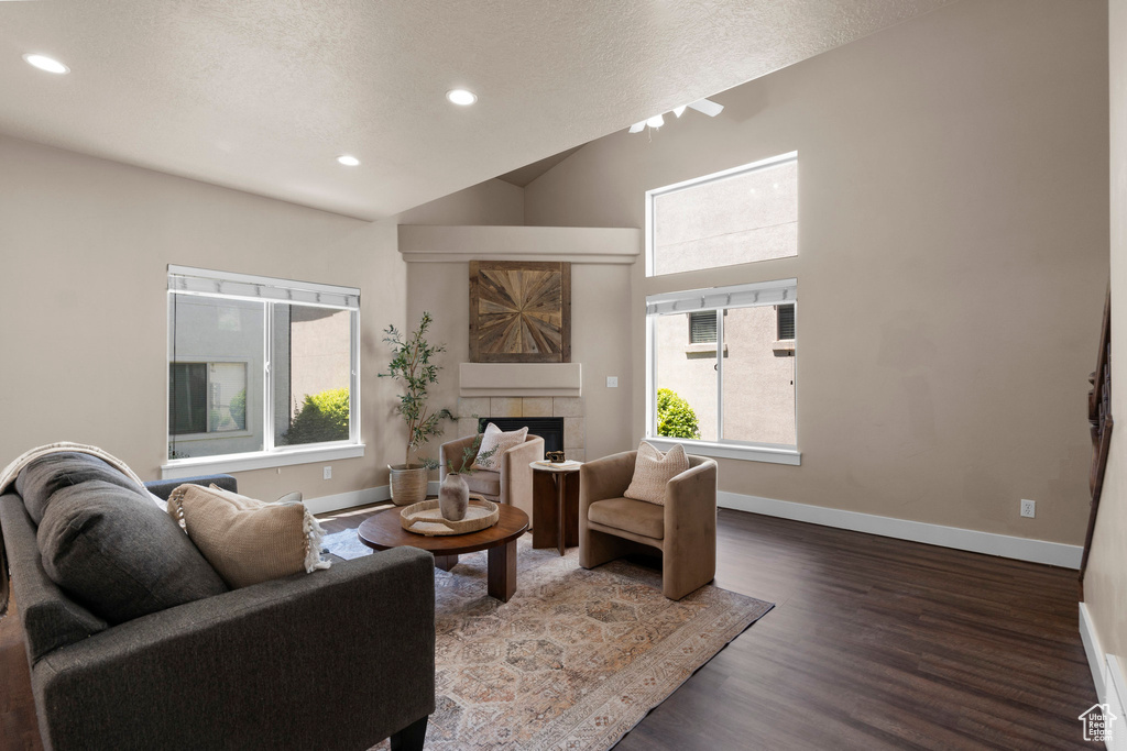 Living area featuring wood finished floors, baseboards, a textured ceiling, recessed lighting, and a tile fireplace
