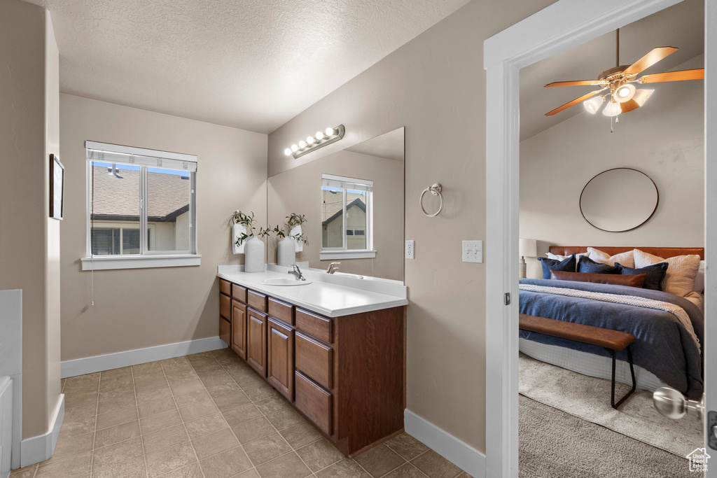 Bathroom with ensuite bathroom, vanity, a ceiling fan, baseboards, and a textured ceiling
