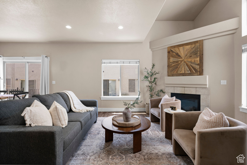 Living area featuring vaulted ceiling, a tile fireplace, recessed lighting, wood finished floors, and baseboards