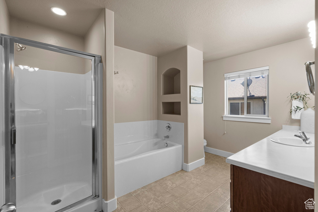 Full bathroom featuring vanity, a stall shower, a garden tub, toilet, and a textured ceiling