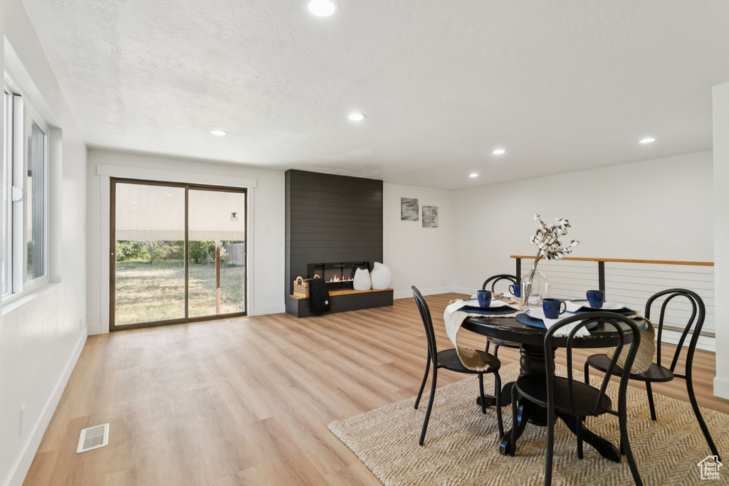 Dining area featuring a large fireplace, baseboards, recessed lighting, and light wood-style flooring