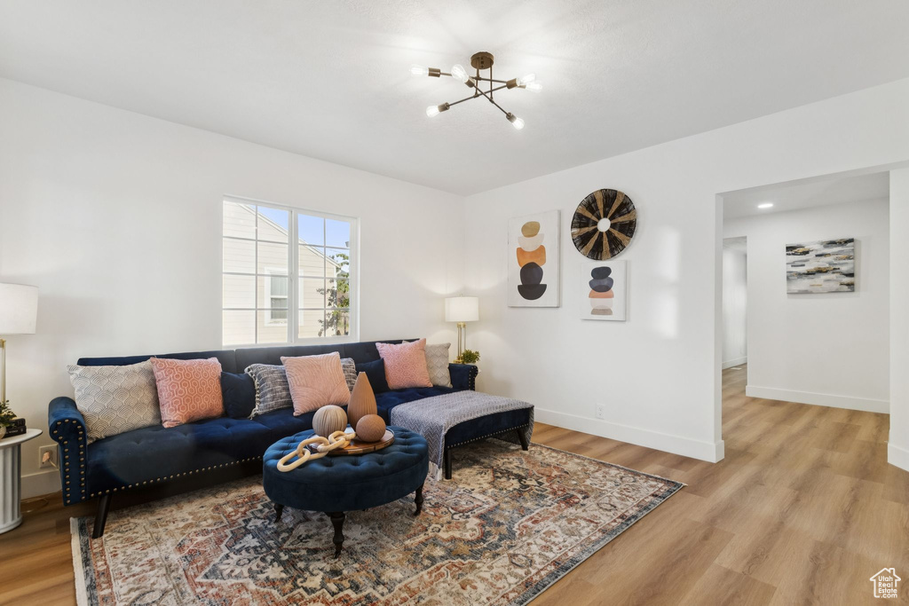 Living room featuring a chandelier, light wood-style flooring, and baseboards