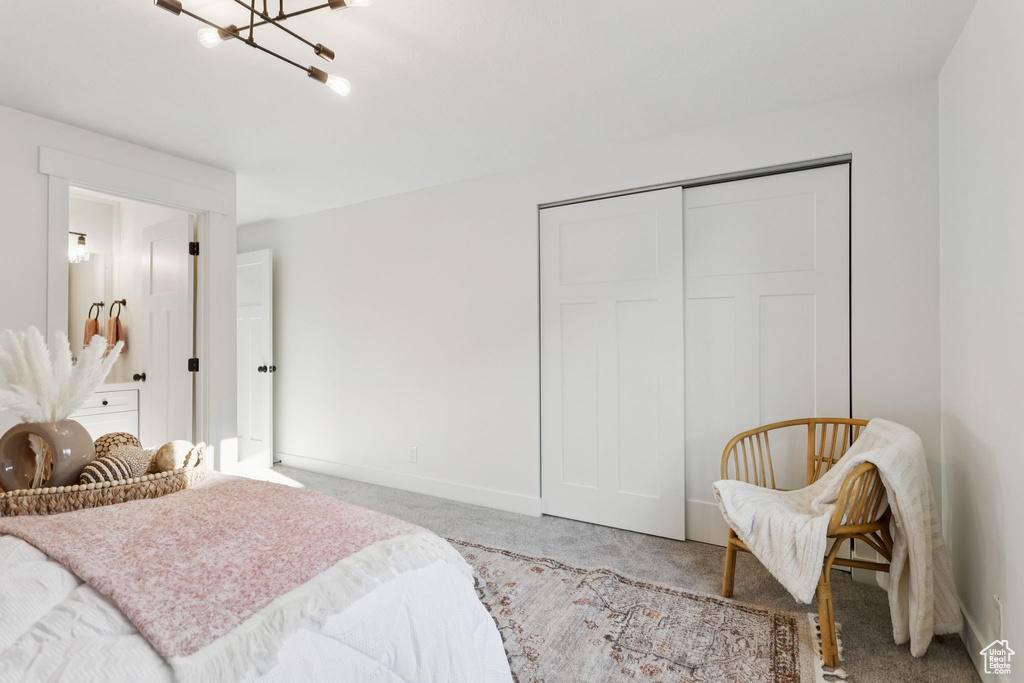 Carpeted bedroom with a closet, baseboards, and a chandelier