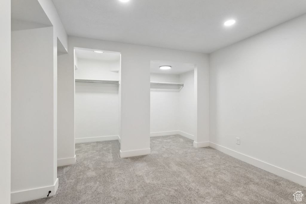 Unfurnished bedroom featuring carpet, baseboards, recessed lighting, and multiple closets