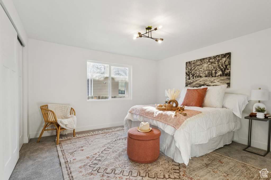 Carpeted bedroom featuring a chandelier, baseboards, and a closet