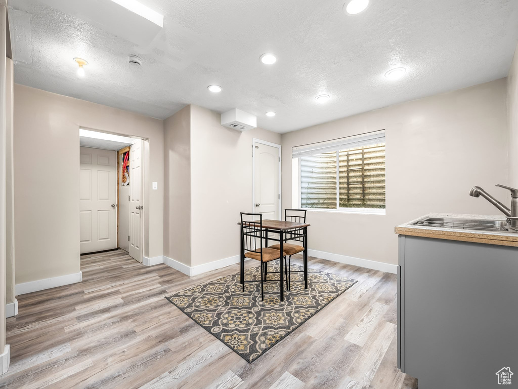 Dining space with a textured ceiling, light wood-type flooring, baseboards, and recessed lighting