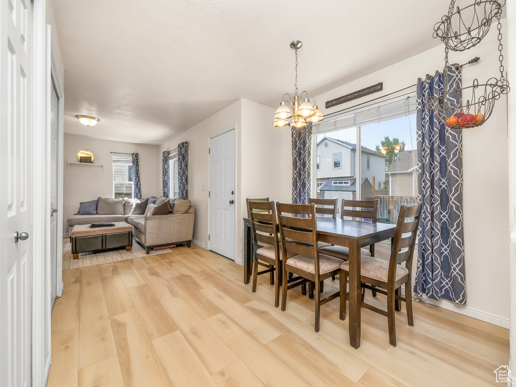 Dining space featuring a chandelier, light wood-style floors, and healthy amount of natural light