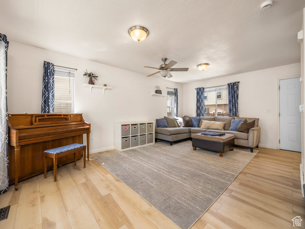 Living room featuring plenty of natural light, wood finished floors, a ceiling fan, and baseboards