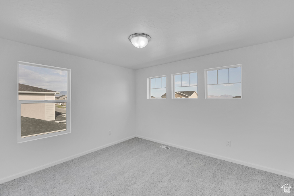 Spare room featuring carpet flooring and baseboards