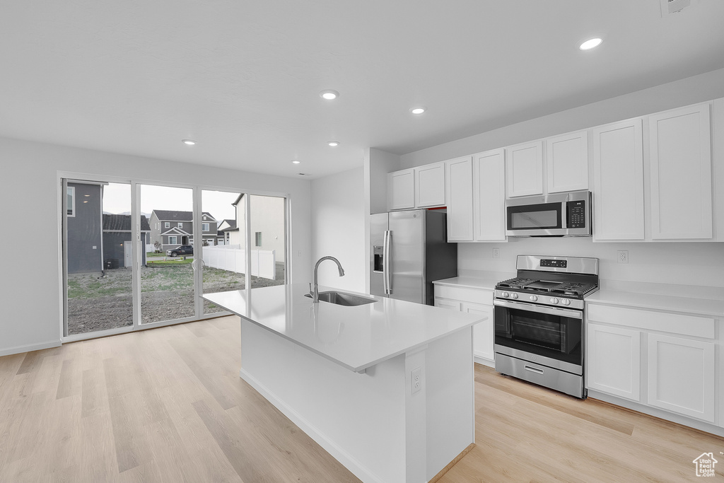 Kitchen featuring stainless steel appliances, a sink, white cabinets, light countertops, and recessed lighting