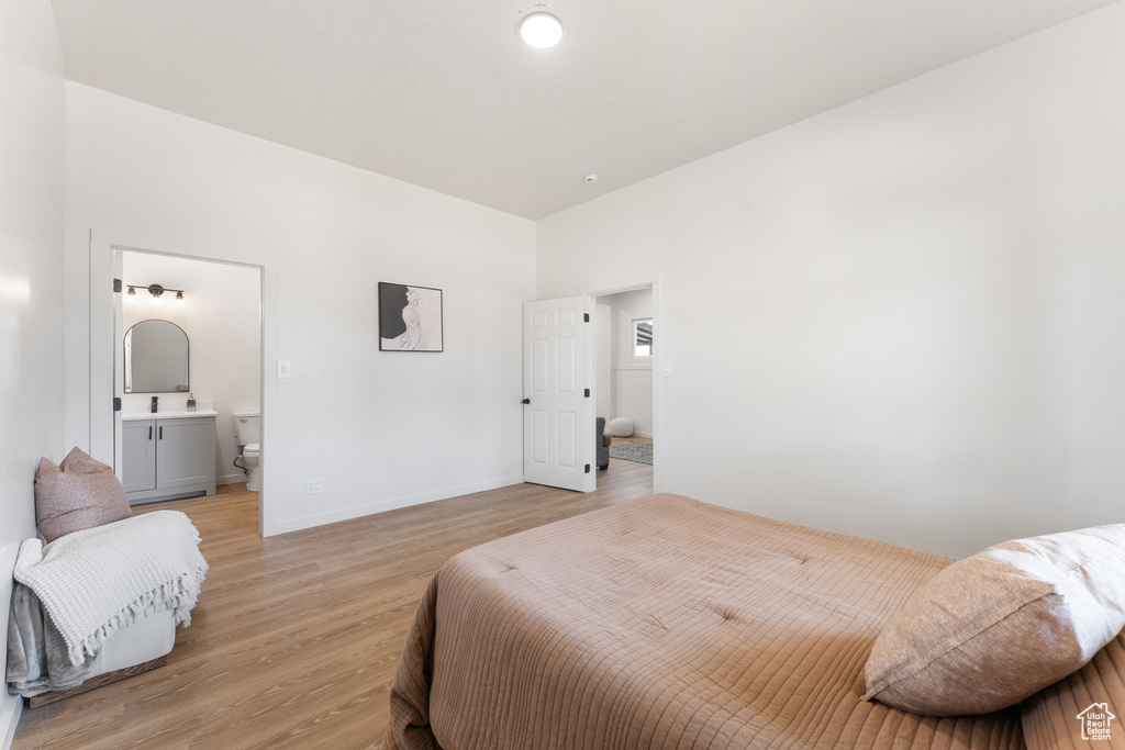 Bedroom featuring light wood-style floors, connected bathroom, and baseboards