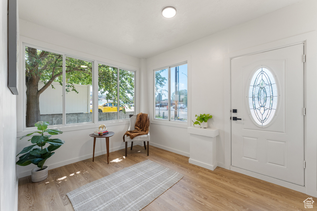 Foyer entrance with healthy amount of natural light, light wood-style floors, and baseboards
