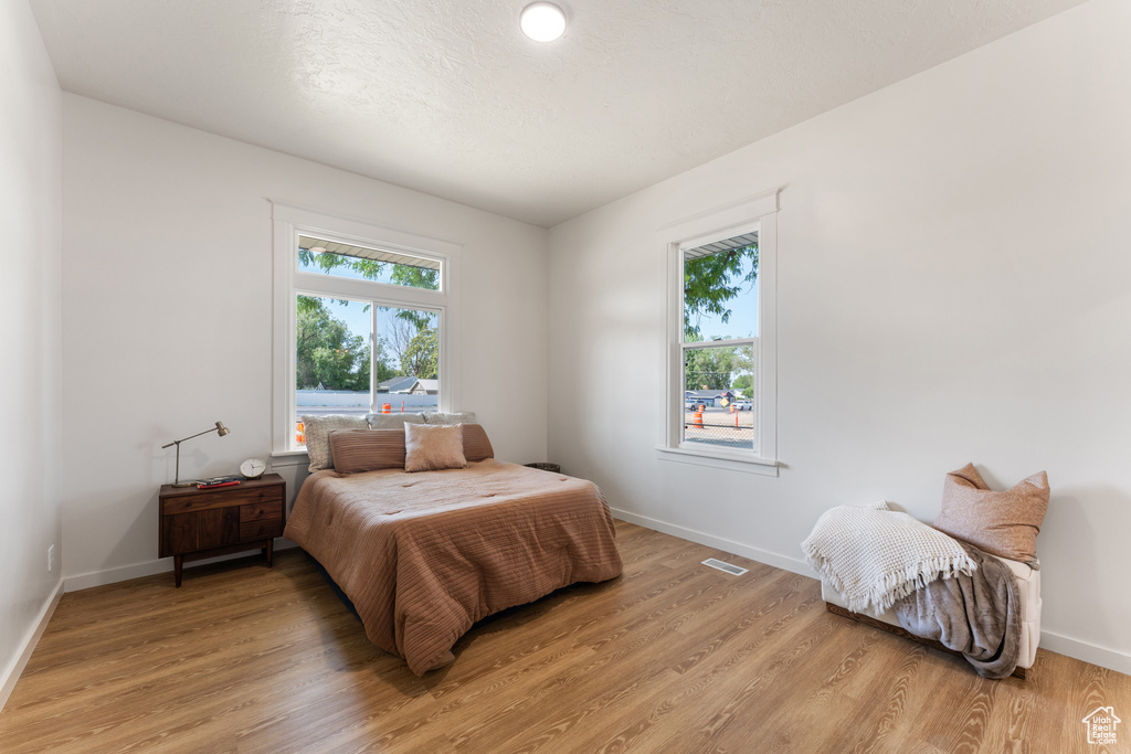 Bedroom featuring multiple windows, light wood-type flooring, and baseboards