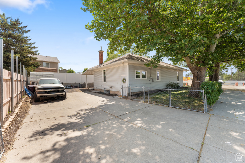 View of front of house with a chimney, concrete driveway, and a gate
