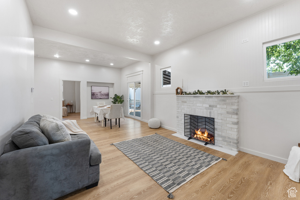 Living area featuring plenty of natural light, recessed lighting, wood finished floors, and a brick fireplace
