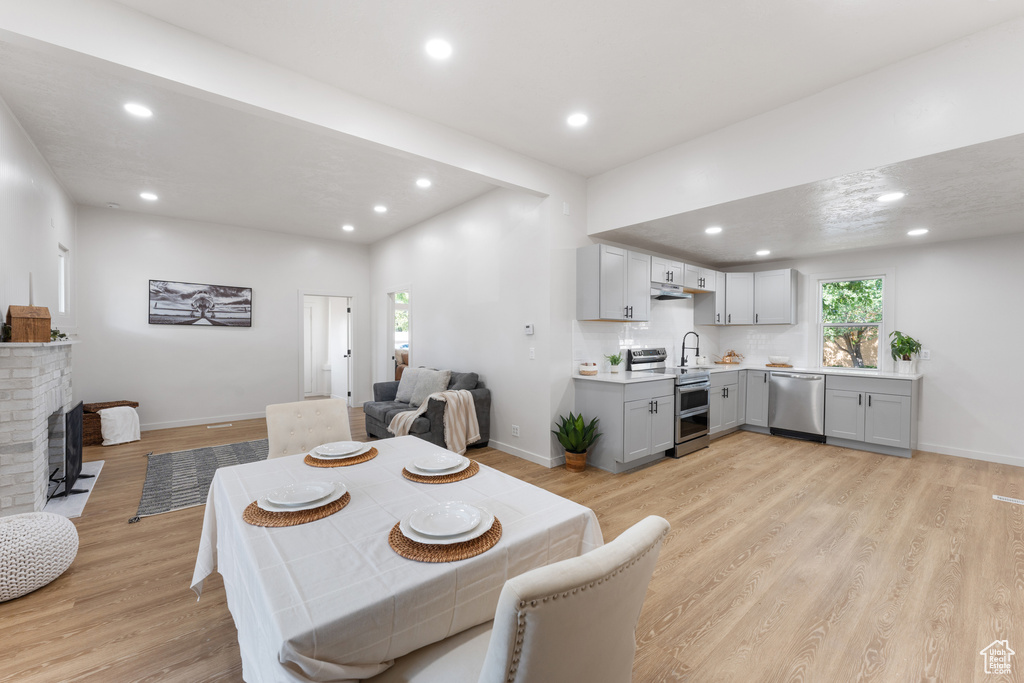 Dining space with baseboards, light wood-type flooring, recessed lighting, and a fireplace