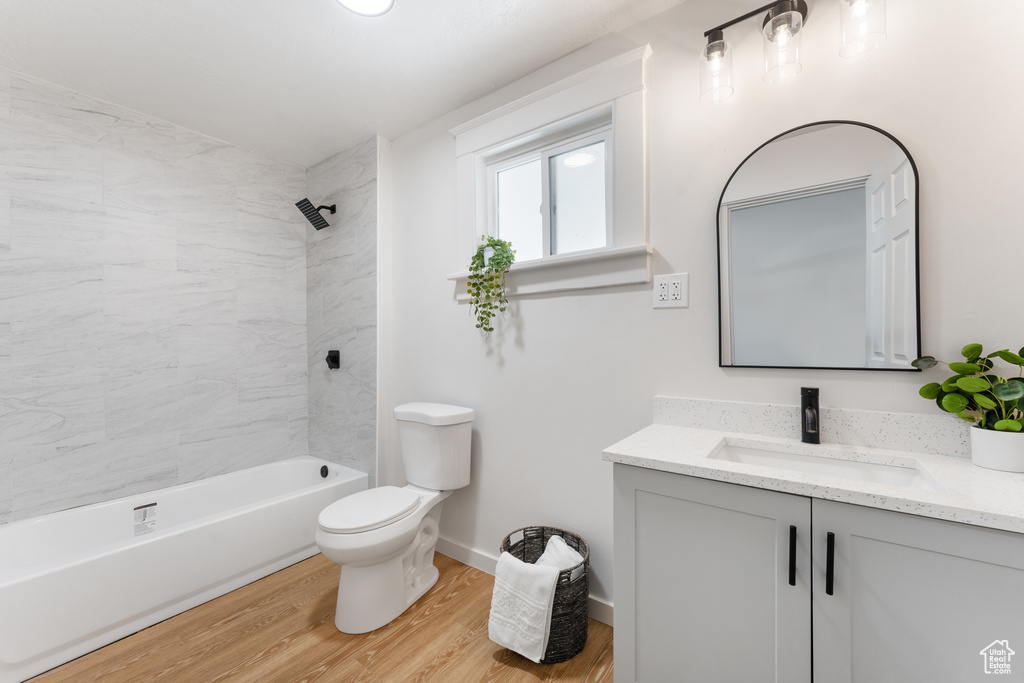 Full bath with vanity, toilet, wood finished floors, tub / shower combination, and baseboards
