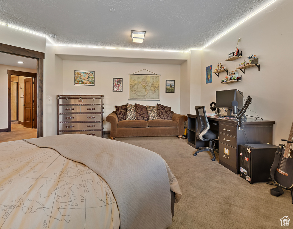 Carpeted bedroom with an office area and a textured ceiling