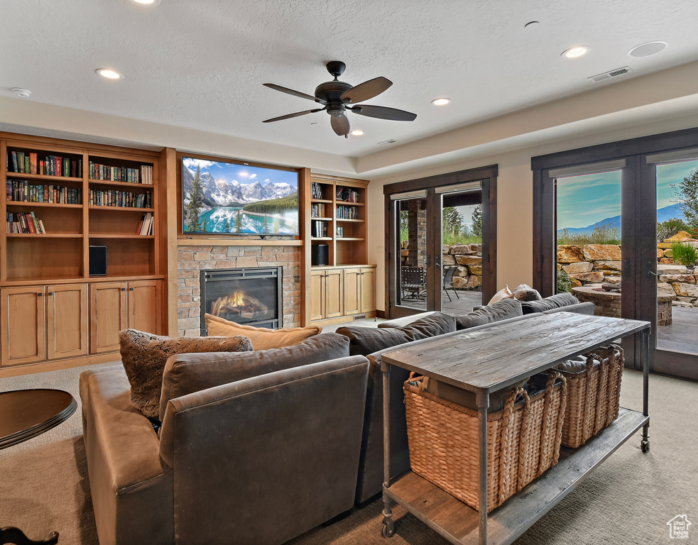 Living room with light carpet, a fireplace, a ceiling fan, recessed lighting, and a textured ceiling