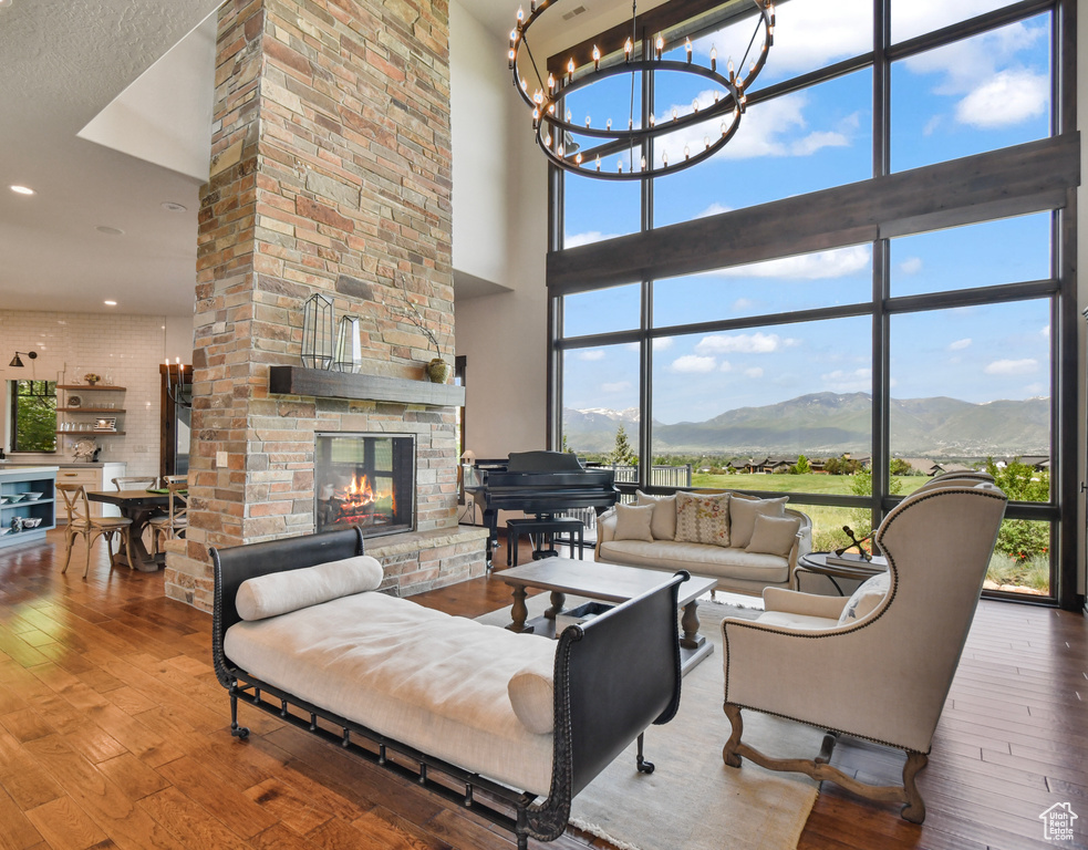 Living room with a high ceiling, a chandelier, a mountain view, a multi sided fireplace, and wood-type flooring