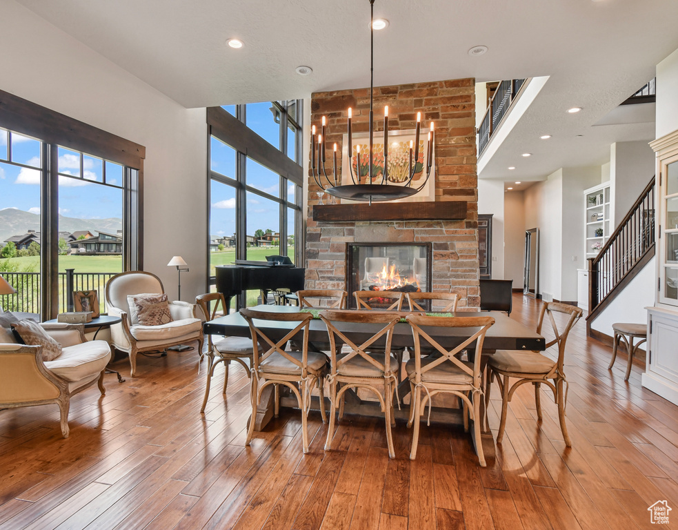 Dining room featuring a multi sided fireplace, plenty of natural light, hardwood / wood-style flooring, a towering ceiling, and recessed lighting