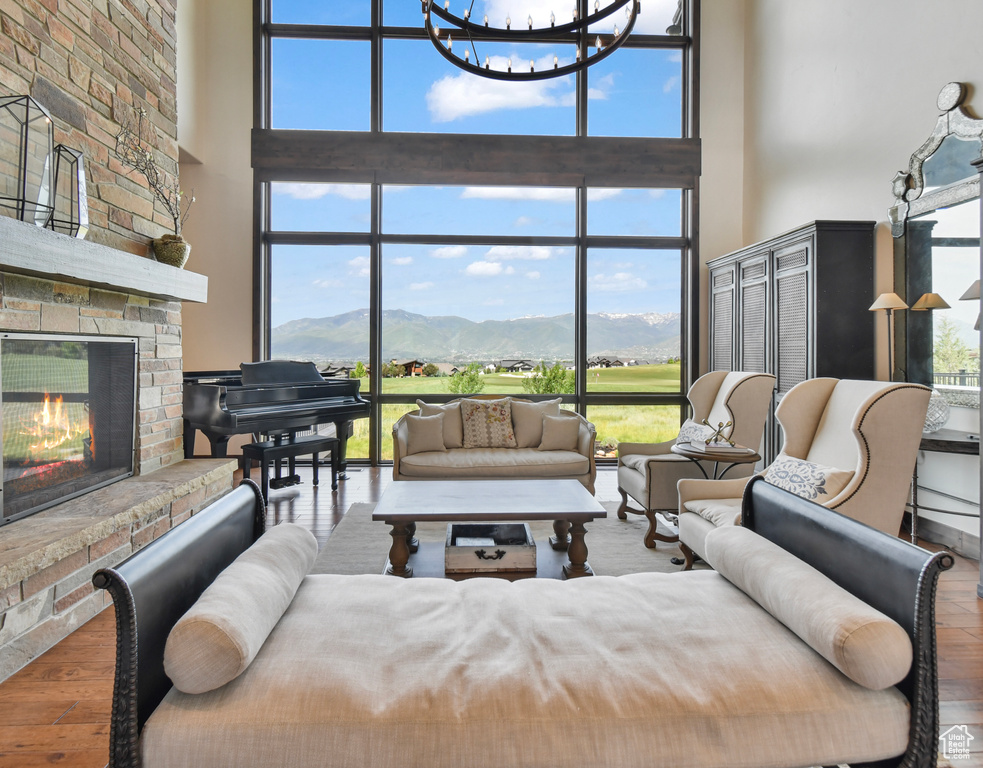 Living area with a high ceiling, a fireplace, a mountain view, a chandelier, and a wall of windows