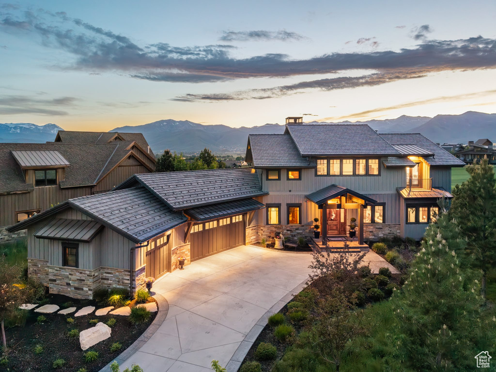 View of front of home featuring stone siding, a mountain view, an attached garage, and concrete driveway