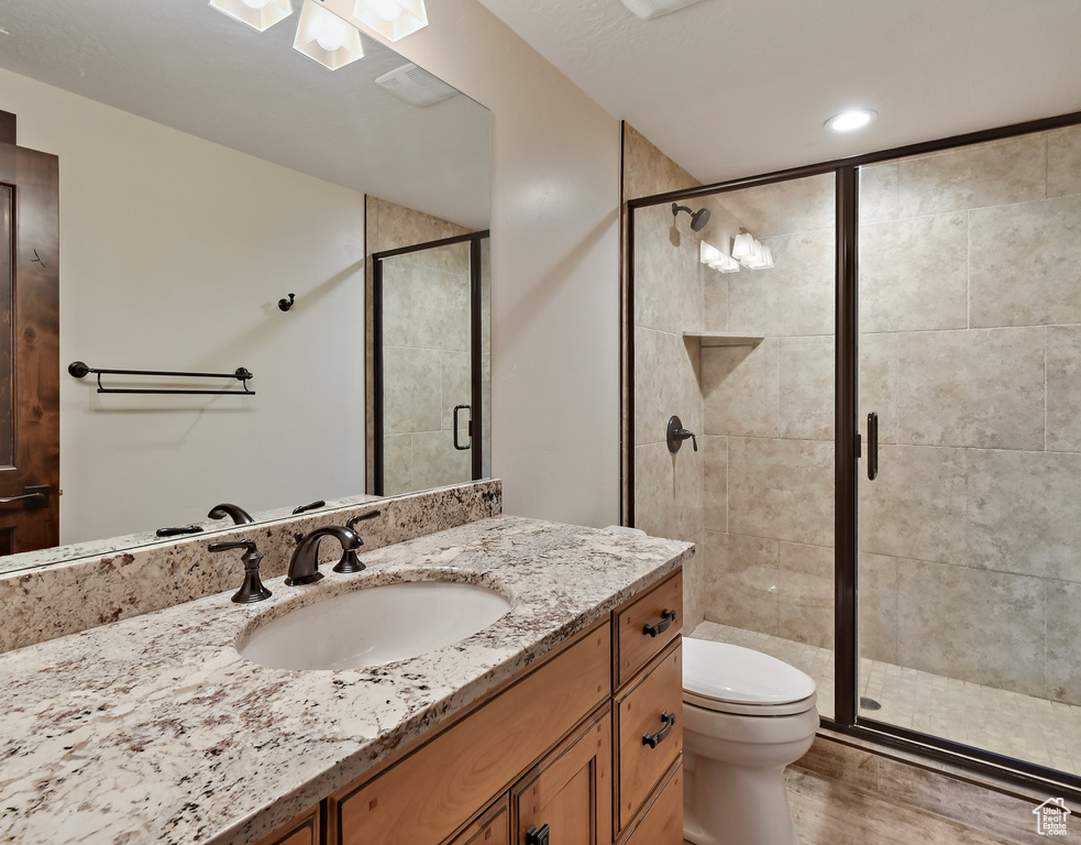 Bathroom with vanity, toilet, a stall shower, and wood finished floors